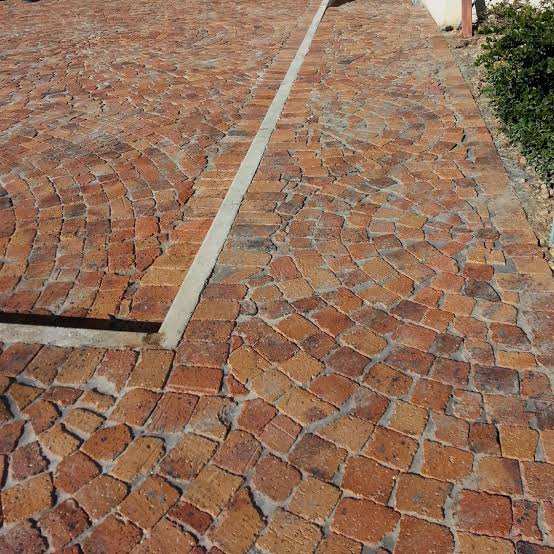 Clay cobble paving laid in a fan pattern beside a concrete channel