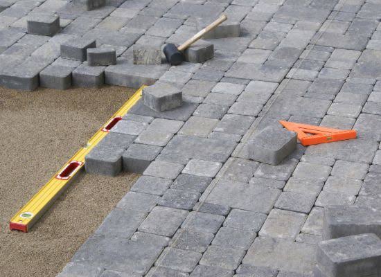 Paving blocks being laid on a levelled sand base with a spirit level