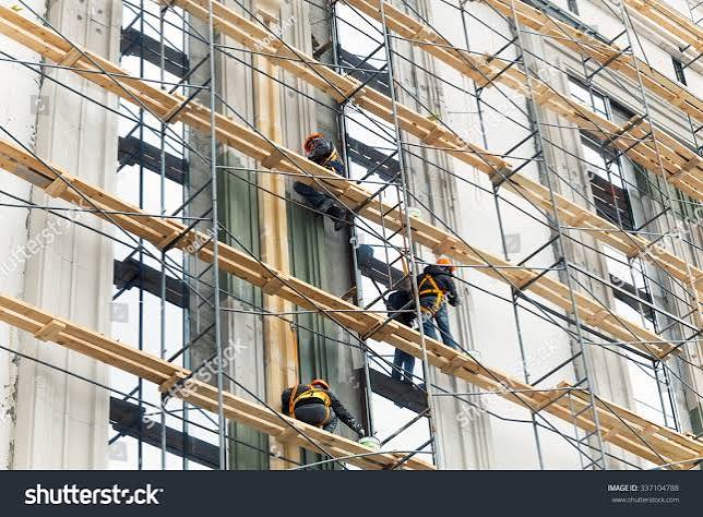 Painters on scaffolding working on a multi-storey building facade