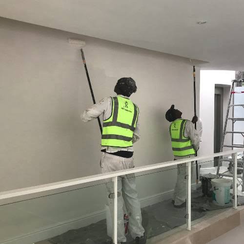 Painters rolling fresh paint onto an interior wall