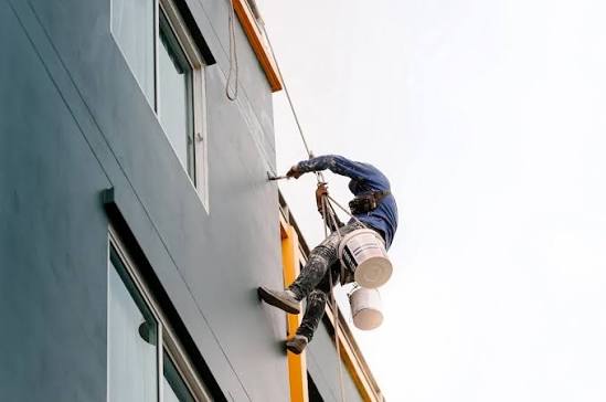 Rope-access painter working on the face of a multi-storey building